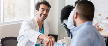 A doctor shaking hands with a person during a meeting