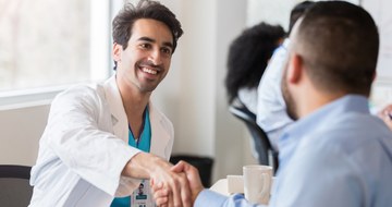 A doctor shaking hands with a person during a meeting