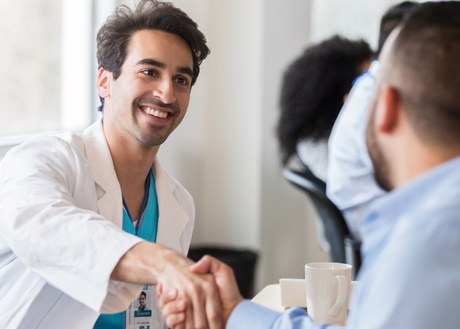 A doctor shaking hands with a person during a meeting