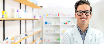 Young man in a pharmacist coat at work